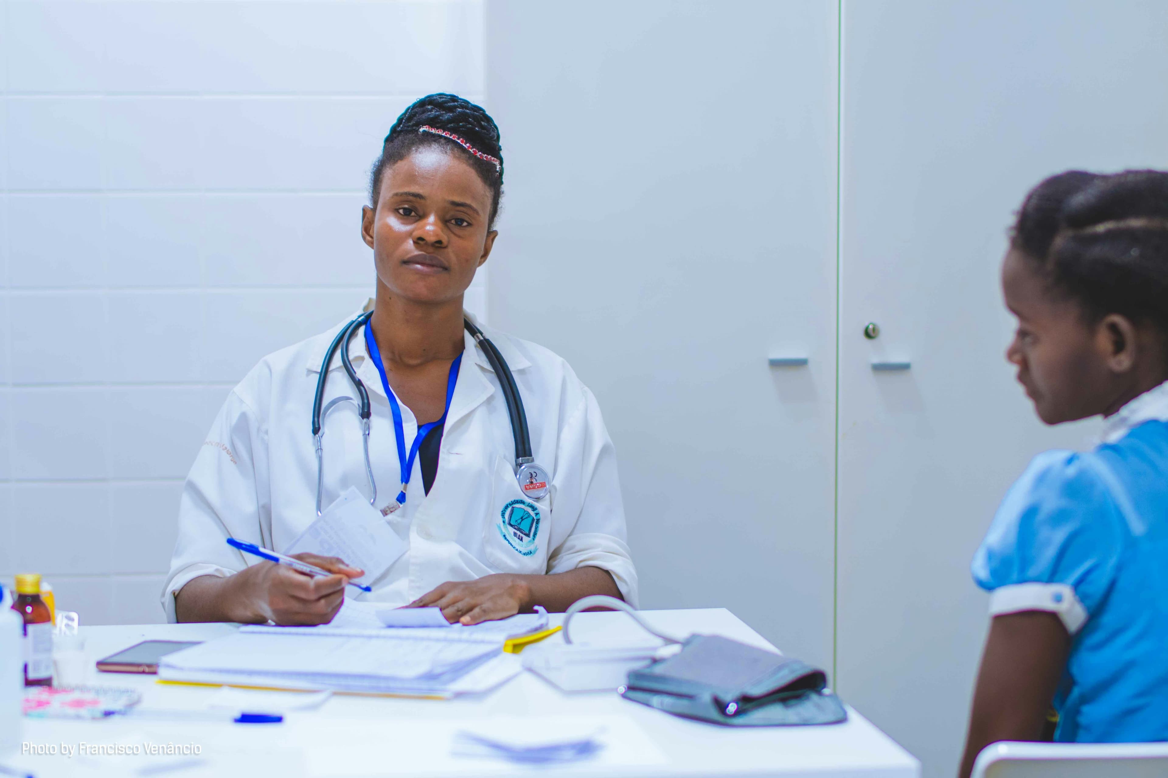 African American pediatrician doctor writing expertise on clipboard