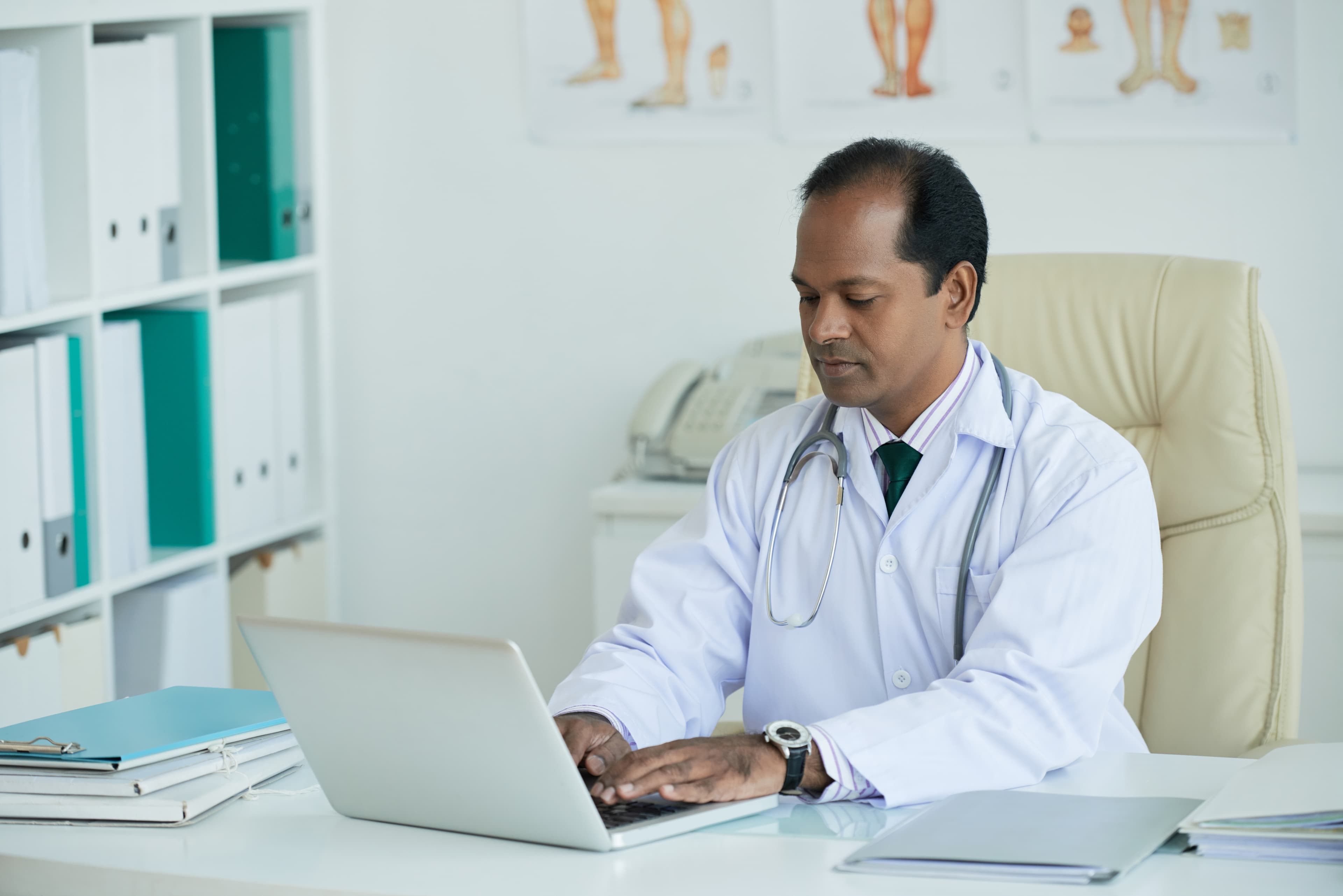 Mature doctor working at a desk on a laptop